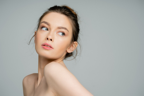 Young woman with naked shoulders looking away isolated on grey  - Photo, image