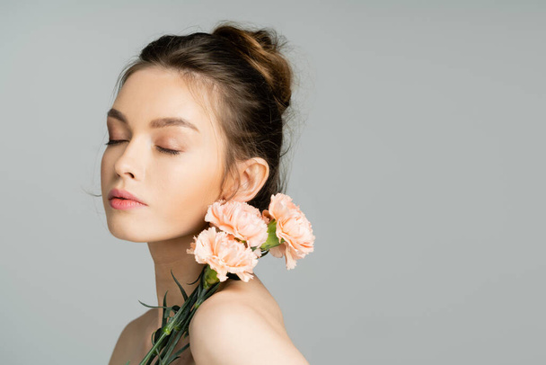 Pretty woman with natural makeup posing with carnations isolated on grey  - Foto, immagini