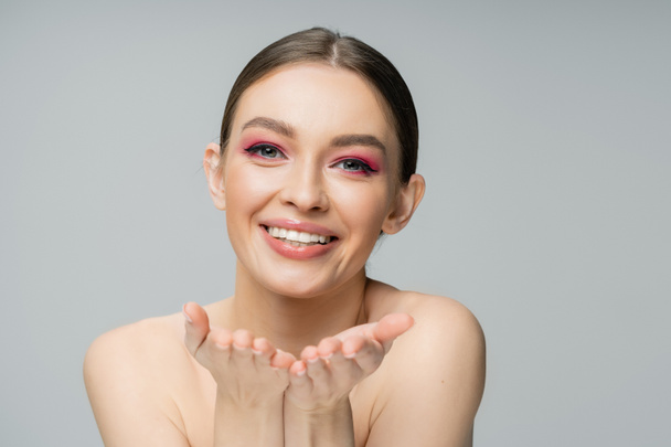 Positive young woman with bright makeup pointing at camera isolated on grey  - Foto, imagen