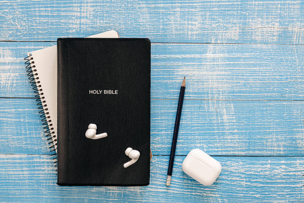 Bijbel, notebook en koptelefoon op een blauwe houten achtergrond, platte lay, kopieerruimte. - Foto, afbeelding