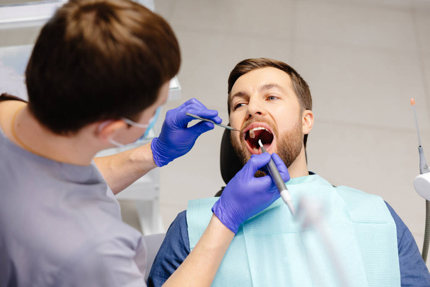Mies tutkituttaa hampaansa hammaslääkärissä. Katsaus hammaskarieksen ehkäisyyn. - Valokuva, kuva