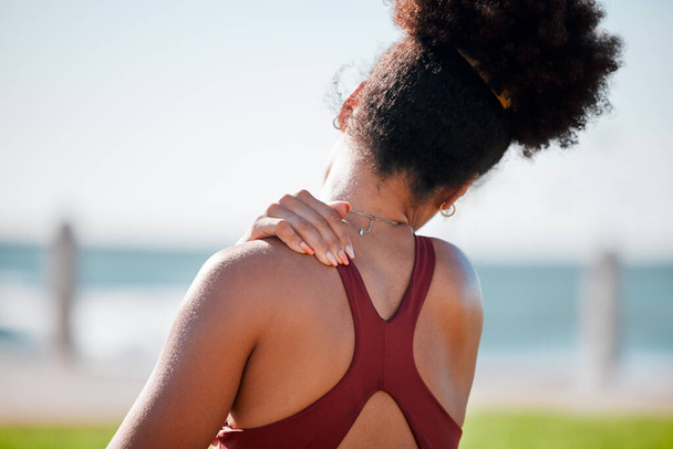 Medical, shoulder pain and fitness with black woman at beach for yoga, workout and exercise training. Burnout, injury and physical therapy with girl in city park for health, sport and pilates goals. - Valokuva, kuva