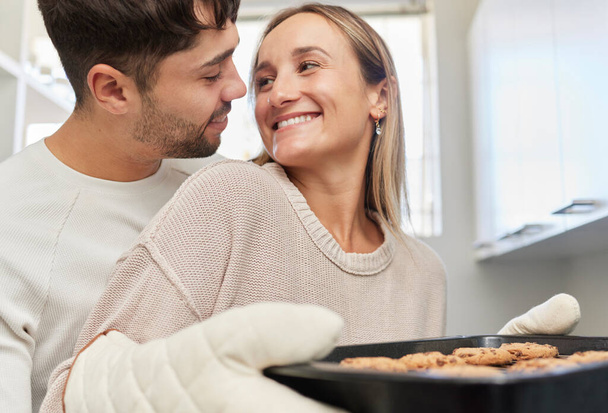 Love, kitchen and couple baking cookies together for fun, bonding and romance in their home. Bake smile and happy young man and woman preparing biscuits or snacks for party, event or dessert at house. - Photo, Image