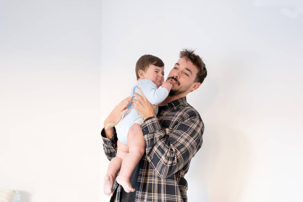 father holding crying baby and trying to soothe him, young father in his twenties, copy space - Photo, Image