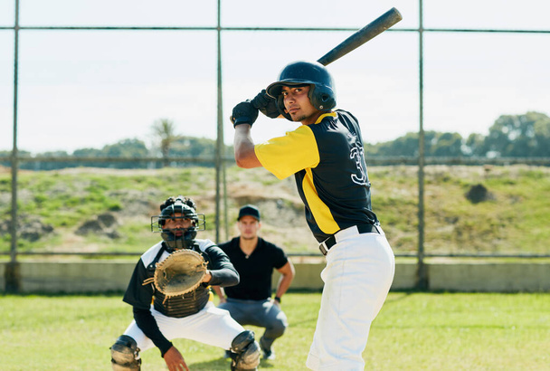 Дай ему биту и смотри, как его страсть вступает в игру. красивый молодой бейсболист готовится бить мячом во время матча на поле - Фото, изображение