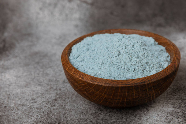 Blue spirulina powder in a bowl on a black marble background. Natural superfood, vegan, healthy food supplement. Phycocyanin extract. Antioxidant. Place for text. Copy space. - Fotoğraf, Görsel