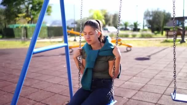 Giovane ragazza in pensiero oscilla su un'altalena catena nel parco. Filmati 4k di alta qualità - Filmati, video