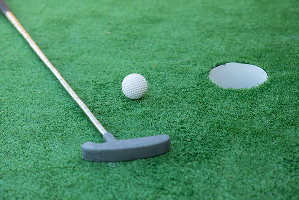 Міні гольф обладнання, гольф клуб, м'яч і дірка на зеленій землі
  - Фото, зображення