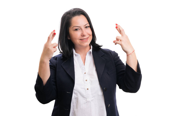 Дружелюбная женщина-предприниматель в формальном костюме улыбается, делая двойной жест удачи пальцы скрещены обеими руками, как бизнес-корпорация концепции изолированы на белом фоне студии - Фото, изображение