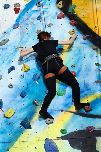 tiener meisje klimt de muur bij de training klimmen muur verliezen-up - Foto, afbeelding