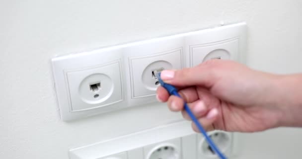 Closeup of woman hand inserting network cable into wall socket. Broadband network concept - Materiaali, video