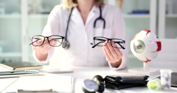 Врач-офтальмолог показывает две пары очков для осмотра глаз. Современная медицина и профессиональный оптик - Кадры, видео