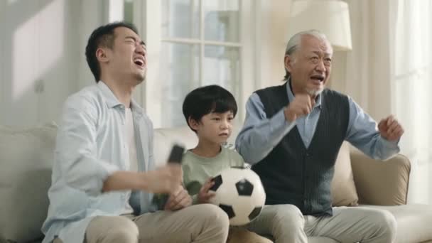Сын азиата отец и дедушка смотрят прямой эфир футбольного матча по телевизору вместе дома и разочарованы выступлением своей команды - Кадры, видео