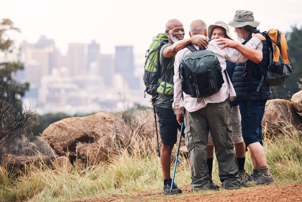 Hiking, city and hug with old men on mountain for fitness, trekking and backpacking adventure with mockup. Support, motivation and expedition with friends on trail for health, retirement and journey. - Photo, Image