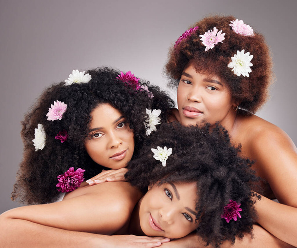 Saç bakımı, arkadaşlar ve stüdyoda çiçekli siyah kadın portresi gri arka planda izole edilmiş. Çiçek kozmetik ürünleri, organik makyaj ve güzellik ve estetik için çiçek taşıyan bir grup kızın yüzü. - Fotoğraf, Görsel