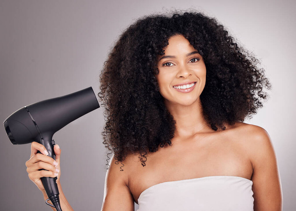 Portrait, beauty and black woman with hair dryer in studio isolated on gray background. Haircare, aesthetic and female model with machine to dry hairstyle after salon treatment for growth or texture - Photo, Image