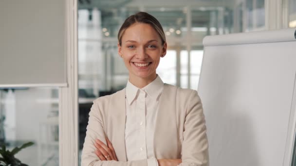 Confident smiling young woman looking at camera standing near office window. Happy millennial casual professional lady with white teeth and blue eyes pretty face posing for close up portrait indoors - Metraje, vídeo