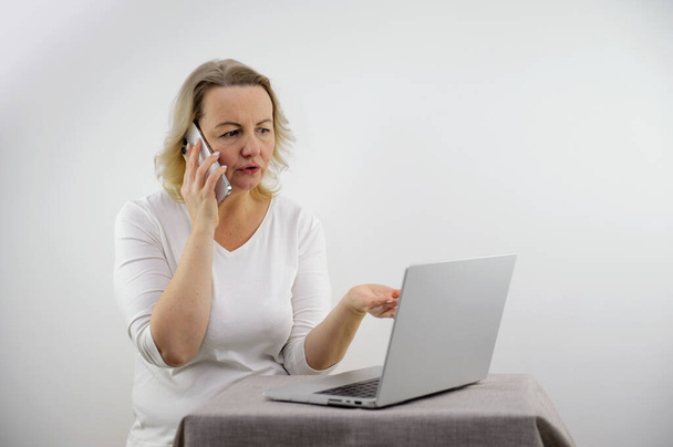 woman talking on phone and pointing with hand at laptop table clarification of relationships problem solving dissatisfied customer home order delivery communication with superiors subordinate children - Fotoğraf, Görsel