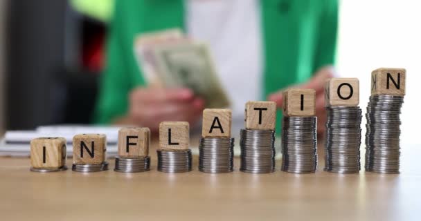 Буквы инфляции на деревянных кубиках и пачки монет на столе. Рост затрат и инфляции - Кадры, видео