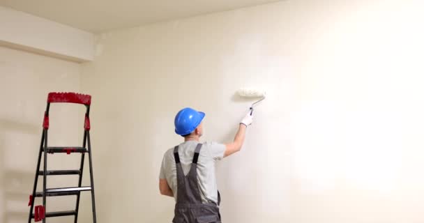 Τοίχοι ζωγραφικής με ρολό σε λευκό χρώμα. Ανακαίνιση διαμερισμάτων και ζωγράφος βάφει τους τοίχους - Πλάνα, βίντεο