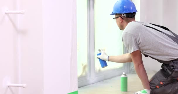 Pintor constructor de pintura pendiente de la ventana con pintura en aerosol blanco. Reparación y pintura de marcos de ventanas - Imágenes, Vídeo