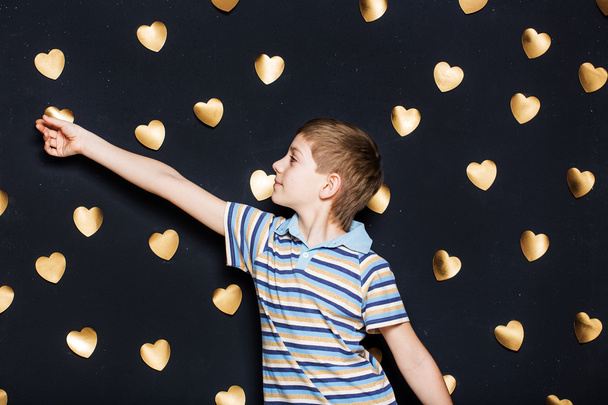 Boy attaching hearts on dark textured background - Fotografie, Obrázek