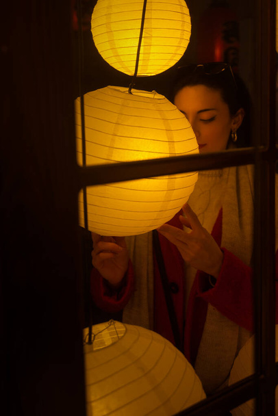 Caucasian white woman with black hair. Portrait with Japanese circular lamps. Warm and soft colors. - Photo, Image