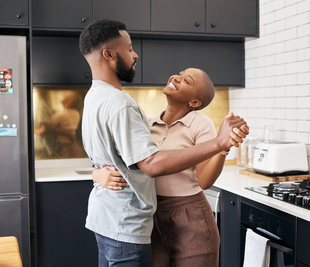 Χορός, αγάπη και ευτυχισμένο μαύρο ζευγάρι στην κουζίνα διασκεδάζοντας μαζί στο νέο σύγχρονο σπίτι τους. Ευτυχία, χαμόγελο και νέοι Αφρικανοί άντρες και γυναίκες χορεύουν για ρομαντικές ή προσωπικές στιγμές στο σπίτι τους. - Φωτογραφία, εικόνα