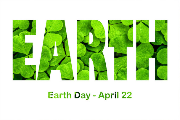 Lettering Earth Day April 22 on the background of clover leaves. Earth day concept, protection of the planet from pollution, improvement of environmental ecology and nature conservation. - Photo, Image