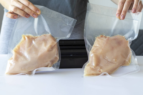 Süpürülmüş tavuk fileto bir kadının elinde ambalaj makinesinin önünde. - Fotoğraf, Görsel