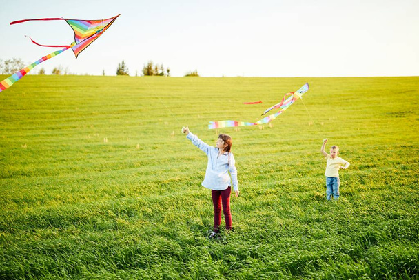 Happy children launch a kite in the field. Little boy and girl on summer vacation. - Photo, Image