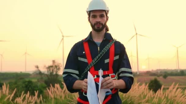 Teamwork two caucasian technicians inspect stands analyzing wind power station area blueprints, generating energy with wind turbines as a clean and environmentally friendly energy force. - Filmmaterial, Video