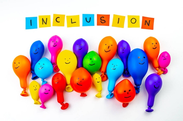 Globos de diferentes colores sobre una superficie blanca, y texto "inclusión". Inclusión, aceptación, integración y diversidad. - Foto, imagen