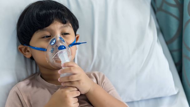 Sick boy inhalation therapy by the mask of inhaler. Baby has asthma and need nebulizations. Patient Boy use inhalation with Nebulizer mask at hospital. The baby are spraying bronchodilators . - Foto, immagini