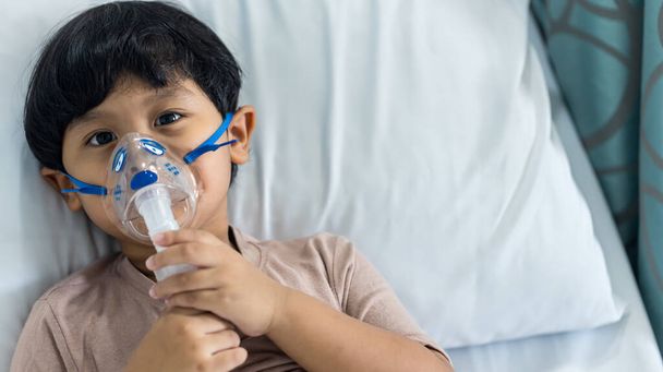 Sick boy inhalation therapy by the mask of inhaler. Baby has asthma and need nebulizations. Patient Boy use inhalation with Nebulizer mask at hospital. The baby are spraying bronchodilators . - Photo, image