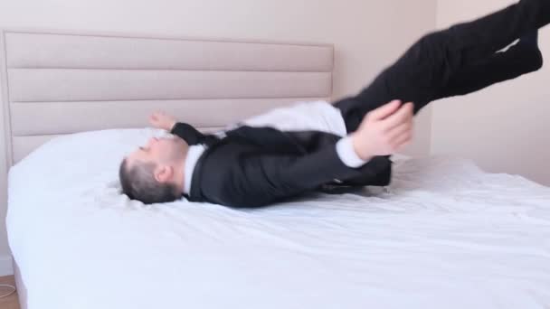 Exhausted businessman in office clothes lying on bed at home after work, side view. Tired after working in the office. 4k video - Footage, Video