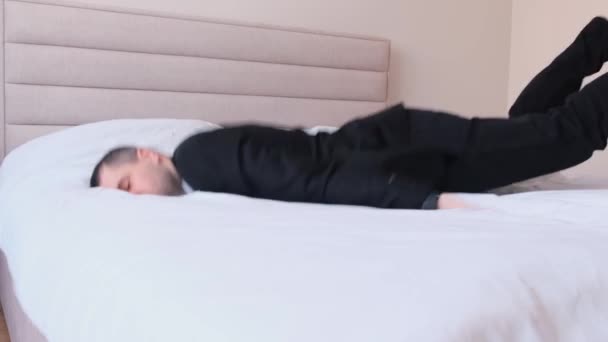 仕事に疲れている。ネクタイでビジネス服を着たハンサムな若い男のトップビュー、目を閉じて、ホテルの部屋にベッドに横たわっている。4kビデオ - 映像、動画