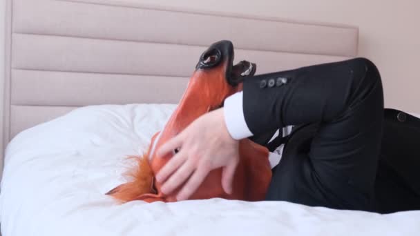A businessman with a horses head is resting in bed, he has a headache. Tired office worker. 4k video - Footage, Video