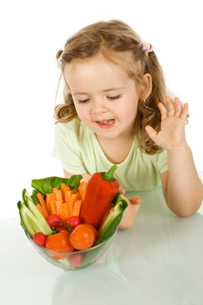 Little girl looking at a bowl of vegetables - Фото, зображення