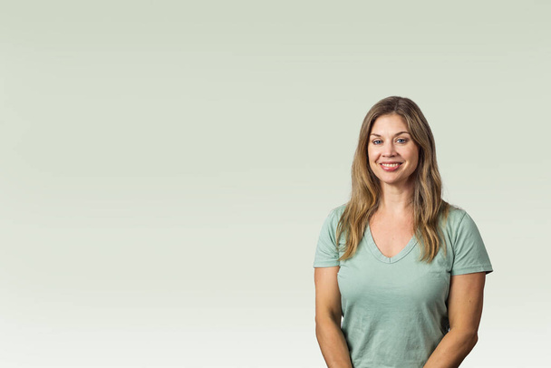 An attractice brunette woman in her forties wearing a green t-shirt against a spring background with copy space. - Photo, Image