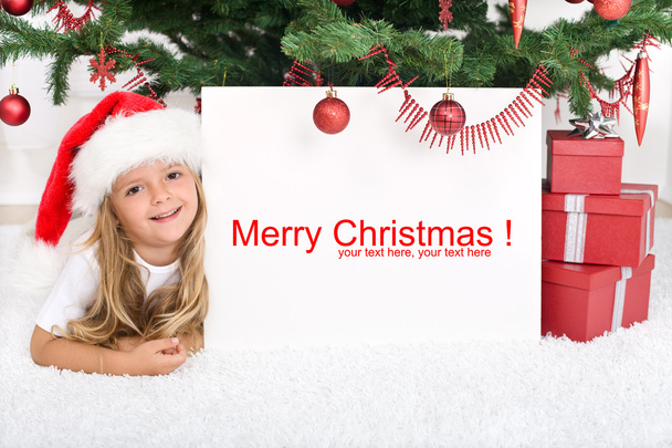 Little girl under the christmas tree with banner - 写真・画像