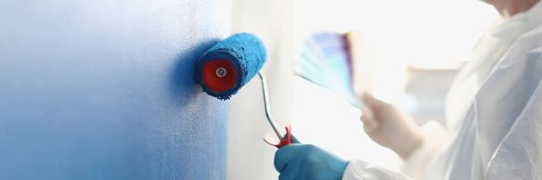 Painting white wall with blue roller. Services of master painter for home repair - Foto, Imagen