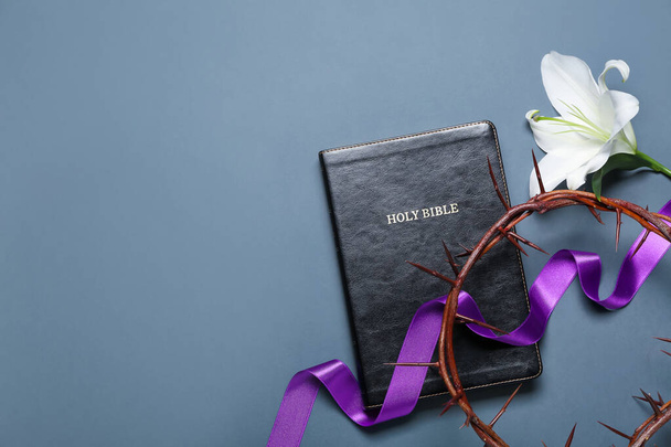 Holy Bible with purple ribbon, crown of thorns and lily flower on blue background. Good Friday concept - Fotó, kép