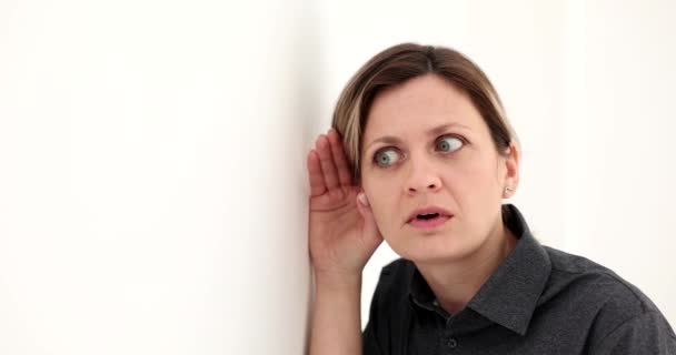 Περίεργη γυναίκα προσπαθεί να ακούσει τι λέγεται πίσω από τον τοίχο. Κρυφακούγοντας προσεκτικά καυτά νέα σε κατάσταση σοκ - Πλάνα, βίντεο