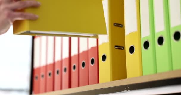 Woman hand puts yellow folder on shelf. Business documentation and document archive - Séquence, vidéo