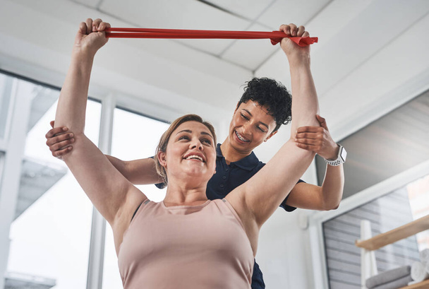 Resistance bands offer simple yet all-round strength building exercises. a young physiotherapist helping her mature patient exercise with a resistance band at a clinic - Foto, Imagen
