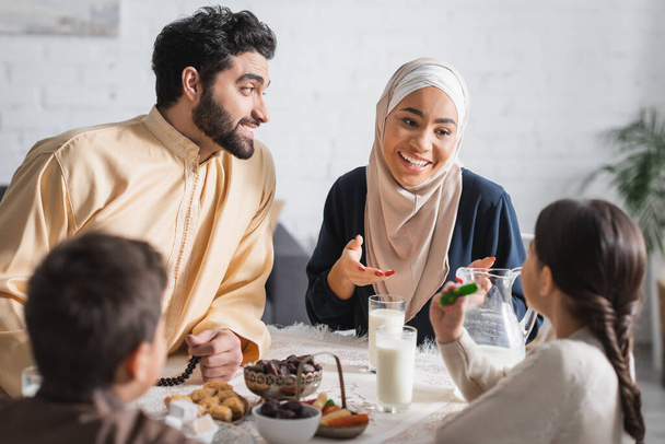 Positive muslim family talking to kids during suhur breakfast at home  - Photo, image
