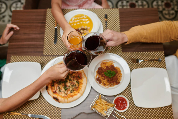 Family toasting over dinner table when celebrating birthday - Фото, изображение