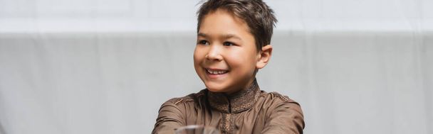 Χαμογελώντας μουσουλμάνε αγόρι κοιτάζοντας μακριά στο σπίτι, πανό  - Φωτογραφία, εικόνα