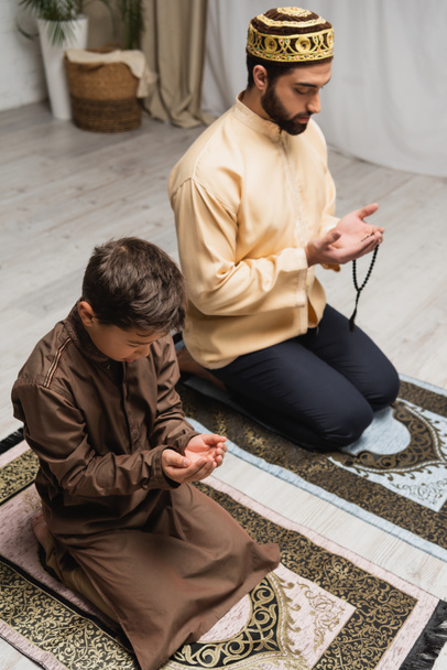 Middle eastern father and son praying during salah at home  - Photo, image